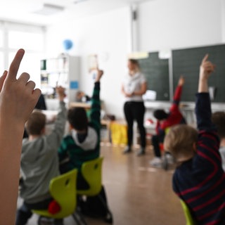 Schülerinnen und Schüler heben in einer Klasse die Hand. In Baden-Württemberg sollen nun die 1.440 Lehrerstellen besetzt werden. (Symbolbild)