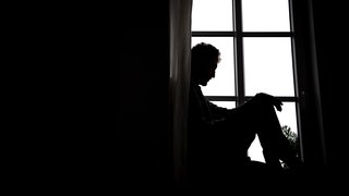 Ein Mann sitzt vor einem Fenster.
