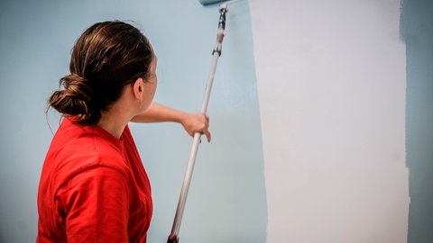 Eine Frau streicht eine Wand an. In Rottenburg muss der Abi-Jahrgang die Wände des Gymansiums in den Ferien streichen. (Symbolbild)