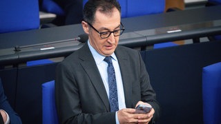 Cem Özdemir schaut im Bundestag auf sein Handy.