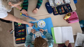 Schüler einer Grundschule arbeiten in einem Klassenzimmer in ihren Heften. 
