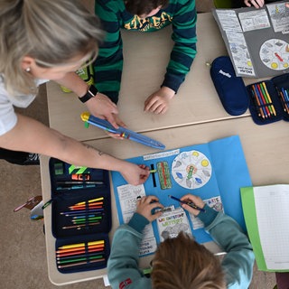 Schüler einer Grundschule arbeiten in einem Klassenzimmer in ihren Heften. 