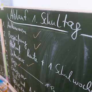 Ein Ablaufplan für den 1. Schultag steht an einer Tafel in einem Klassenzimmer. 