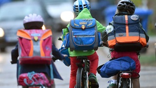 Kinder sind auf einer Straße mit dem Fahrrad unterwegs zur Schule.