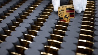 Ein Mitarbeiter nimmt ein Porsche-Logo aus einem Kasten voller Logos. 