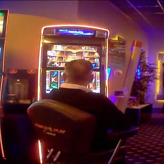 Männer sitzen vor Glücksspielautomaten