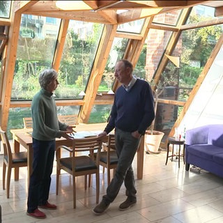Ein Ehepaar steht in einem Wohnzimmer und spricht miteinander