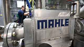 Ein Mitarbeiter des Automobilzulieferers Mahle bereitet einen Wasserstoff Motor für einen Testlauf in einem Teststand vor. Der Autozuleiferer will weltweit weitere 1.000 Stellen streichen.
