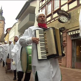 Narren ziehen verkleidet und mit Musik durch die Straßen