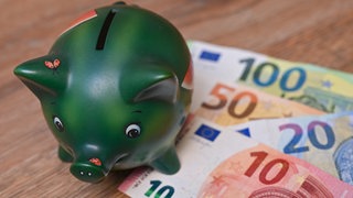  Ein Sparschwein steht auf einem Tisch neben Eurobanknoten. Faste alle Kommunen in Baden-Württemberg müssen sparen.