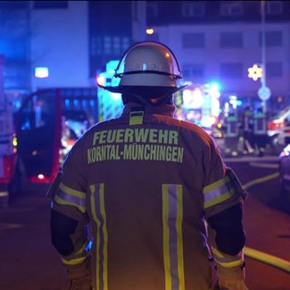 Ein Feuerwehrmann vor mehreren Feuerwehrautos in der Silvesternacht