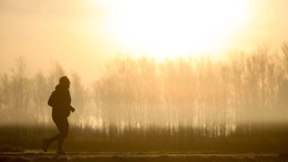 Ein Jogger ist am Morgen im Gegenlicht der Sonne unterwegs, während sich der Himmel durch Saharastaub gelb verfärbt hat. 