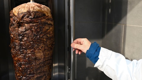 Ein Lebensmittelkontrolleur begutachtet bei einer Kontrolle in einem Imbiss in Stuttgart den Dönergrill.