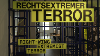 Vor Gefängniszellen ist Text eingeblendet. Dort steht: "Rechtsextremer Terror. Right-Wing Extremist Terror". Eine Ausstellung zeigt die Geschichte des Rechtsterrorismus in Baden-Württemberg von der Weimarer Republik bis in die Gegenwart.