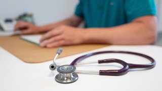 Ein Hausarzt sitzt in einem Sprechzimmer seiner Praxis. Die geplante Gesundheitsreform sorgt für viel Kritik bei den Ärzten. (Symbolbild)