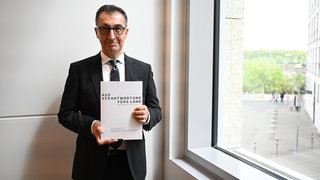 Der zukünftige Ministerpräsident Cem Özdemir (Grüne) hält den Koalitionsvertrag von Grünen und CDU in den Händen. 