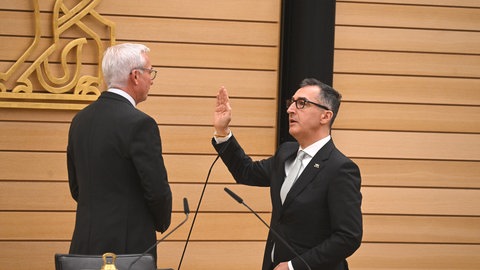 Ministerpräsident Cem Özdemir hebt die rechte Hand zum Amtseid vor Landtagspräsident Thomas Strobl.