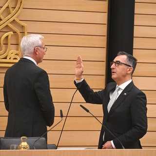 Ministerpräsident Cem Özdemir hebt die rechte Hand zum Amtseid vor Landtagspräsident Thomas Strobl.