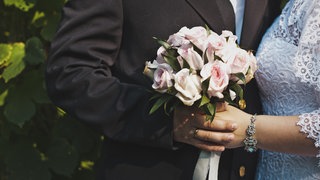 Bild eines Brautpaares mit Brautstrauß: Hochzeiten werden immer pompöser und teurer. Was haben soziale Medien damit zu tun? (Symbolfoto)
