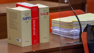 Die Strafprozessordnung (StPO), das Strafrecht und das Strafgesetzbuch (StGB) stehen vor Gericht auf einem Tisch.