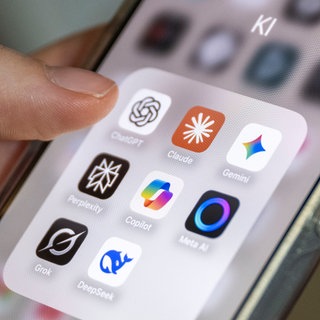 Auf einem Smartphone-Bildschirm sind mehrere KI-Anwendungen zu sehen, darunter ChatGPT, Claude, Gemini, Perplexity, Microsoft Copilot, Meta AI, Grok und DeepSeek.
