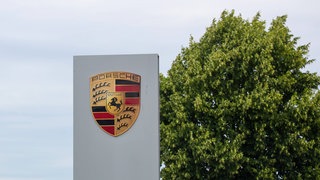 Firmenlogo des Sportwagenbauers Porsche. Porsche könnte laut einem Medienbericht weitere 4.000 Stellen abbauen. Im Entwicklungszentrum in Weissach stehen 30 Prozent der Stellen auf dem Prüfstand.