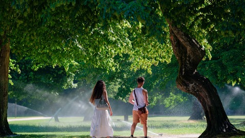 Eine Frau und eine Mann laufen im Sommer durch den Heidelberger Schlosspark. Am Donnerstag könnten wieder Temperatur-Rekorde geknackt werden.