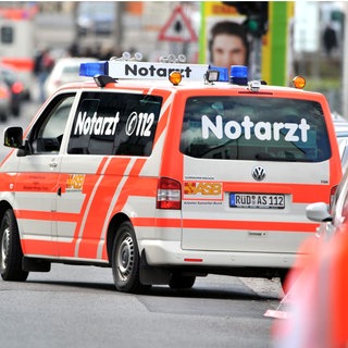 Ein Notarztwagen fährt auf eine Straße. 