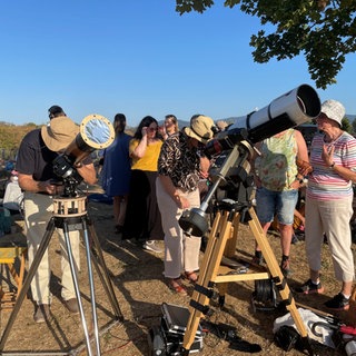 Menschen warten mit ihrem Teleskop auf die Sonnenfinsternis.