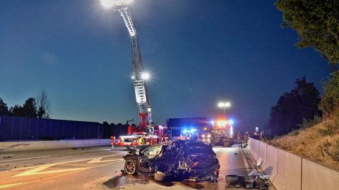 Ein Auto mit Totalschaden liegt auf der Fahrbahn der A81. Im Hintergrund ist die Feuerwehr im Einsatz.