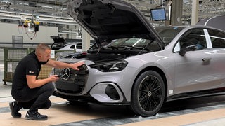 Ein Mercedes-Mitarbeiter prüft in einem Werk die Qualität eines Autos