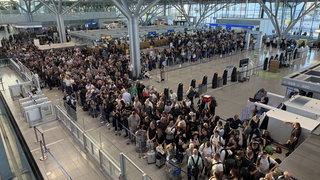 Nachdem der Flugbetrieb am Stuttgarter Flughafen am Montagnachmittag kurzzeitig eingestellt wurde, stehen viele Reisenden dicht gedrängt in der Abflughalle.
