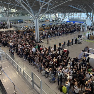 Nachdem der Flugbetrieb am Stuttgarter Flughafen am Montagnachmittag kurzzeitig eingestellt wurde, stehen viele Reisenden dicht gedrängt in der Abflughalle.
