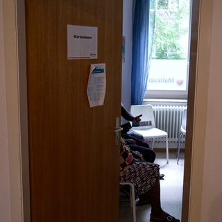 Mehrere Personen sitzen in einem Wartezimmer der Stuttgarter Praxis der Malteser-Medizin für Menschen ohne Krankenversicherung.