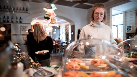 eine junge Frau ohne Maske am Buffet