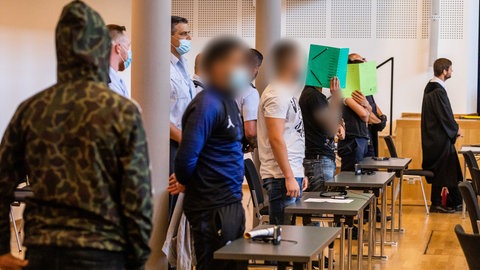 Fünf Angeklagte stehen hinter Tischen in dem zum Gerichtssaal umfunktionierten Paulussaal. Wegen der Gruppenvergewaltigung einer 18-Jährigen in Freiburg Mitte Oktober 2018 sind die meisten der elf Angeklagten zu Haftstrafen verurteilt worden.