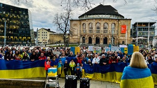 Mehrere Menschen tragen die Farben der ukrainischen Flagge am Körper oder als Fahne.