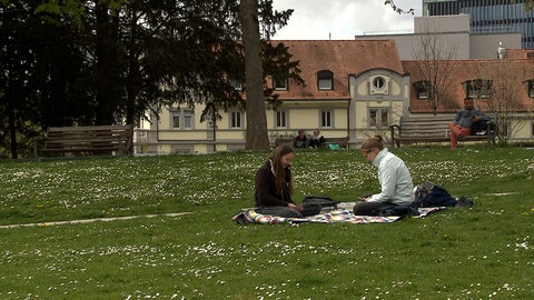 Zwei junge Frauen auf einer Picknickdecke im Freiburger Colombipark