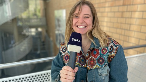 Man sieht eine Reporterin mit einem SWR Mikrofon in der Hand.