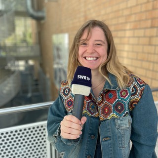 Man sieht eine Reporterin mit einem SWR Mikrofon in der Hand.