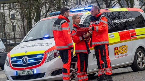 Drei Mitglieder vom Münchner Kriseninterventionsteam KIT-München stehen zusammen an einem Einsatzwagen. Das erste Kriseninterventionsteam in Deutschland und auch weltweit wurde 1994 in München im Arbeiter-Samariter-Bund gegründet.