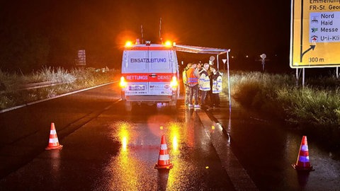 Einsatzkräfte und das Kriseninterventionsteam stehen an einer abgesperrten Straße in Freiburg nach einem Unfall mit mehreren Toten.