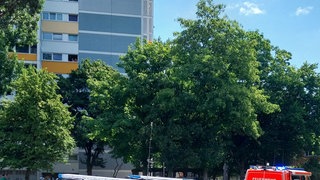Feuerwehr und Polizei stehen vor einem Hochhaus in Freiburg, in dem ein Brand gemeldet wurde.