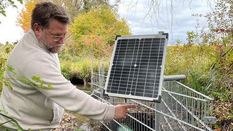 Ein Mann zeigt auf ein kleines Solarpanel.