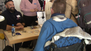 Ein Mann im Rollstuhl sitzt an einem Tisch. Er lässt sich bei der inklusiven Jobmesse beraten.
