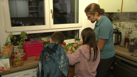 Zwei der Pflegekinder helfen ihrem Papa beim Kochen.
