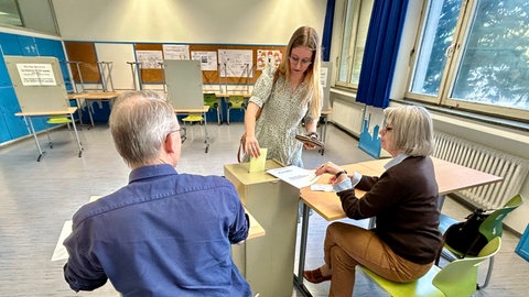 Frau wirft ihren Wahlzettel für die Oberbürgermeister-Wahl in Freiburg in die Urne