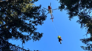 Rettungskräfte von DRF Luftrettung und Bergwacht werden in den Rettungshubschrauber gezogen.