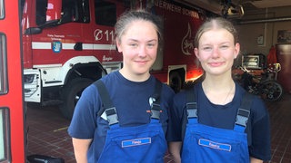 Die Teenager Finnja Kaltenbach und Emely Langenbach stehen nebeneinander im Eingang zum Feuerwehrhaus in Schwanau. Die Jugendfeuerwehr hat hier seit Jahren großen Zulauf. 