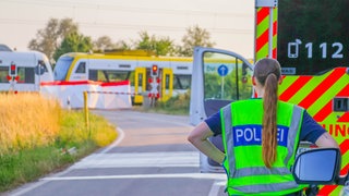 Eine Polizistin vor einem abgesperrten Bahnübergang